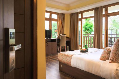 a bedroom with a bed and a desk with a computer at Yashshree Karbari Resort & Spa in Yangang