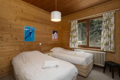 une chambre avec deux lits dans une cabane en rondins dans l'établissement Grand Chalet Les 4 Vents, Morzine, vue sublime, à Morzine