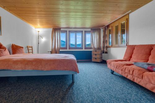 a bedroom with a bed and a couch and a window at Sérénité Spiez, Lakeview, Chalet in Einigen