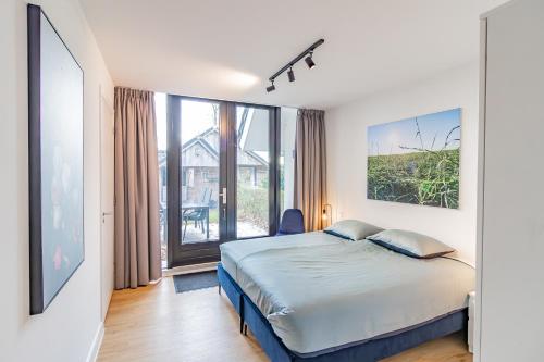 a bedroom with a bed and a large window at Boerderijkamer Ochtendzon in Lutten