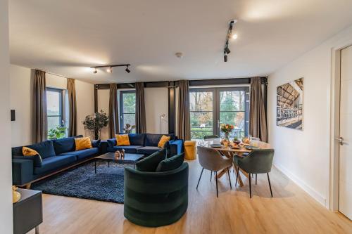 a living room with a blue couch and a table at Appartement Ochtendzon in Lutten