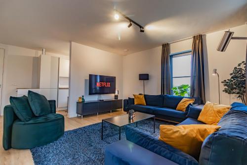 a living room with blue couches and a tv at Boerderijkamer Ochtendzon in Lutten