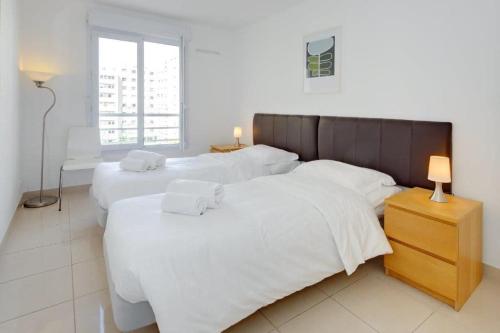 une chambre avec deux lits avec des draps blancs et une fenêtre dans l'établissement Villa Kappas - B42 Promenade des Anglais, à Nice