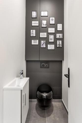La salle de bains est pourvue de toilettes noires et d'un lavabo. dans l'établissement V2D Vivid Elegance near Palais Royal 4P, à Paris