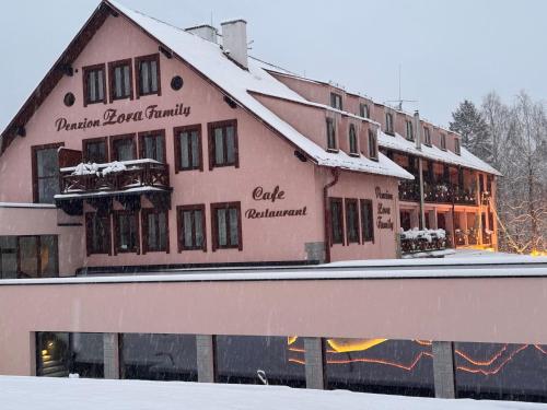 a large building with snow on top of it at Wellness Penzion Zora Family in Tatranská Lomnica