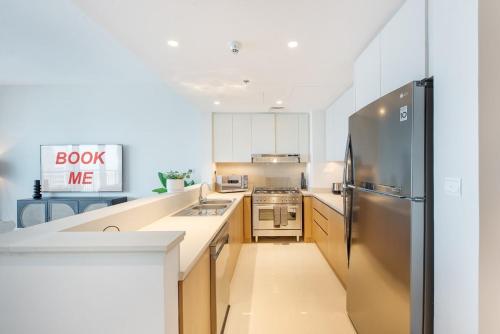 a kitchen with white cabinets and a stainless steel refrigerator at Free housekeeping visits during your stay - StayShort - Stylish Cozy 3-Bedroom Apartment with Harbour Views in Dubai Creek Harbour in Dubai
