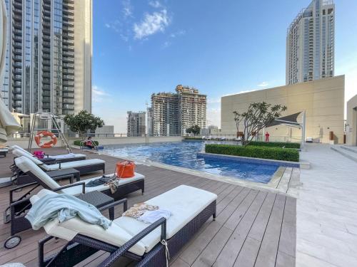 a swimming pool with lounge chairs on a rooftop at Free housekeeping visits during your stay - StayShort - Stylish Cozy 3-Bedroom Apartment with Harbour Views in Dubai Creek Harbour in Dubai