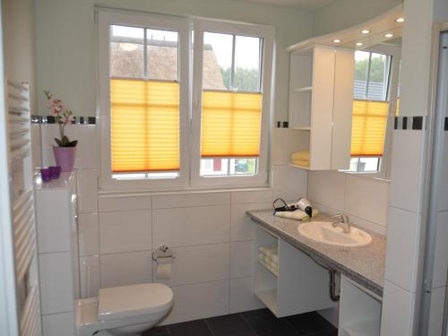 グロヴェにあるFerienhaus Godewind Gloweのバスルーム(トイレ、洗面台付)、窓2つが備わります。