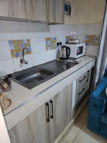 a small kitchen with a sink and a microwave at The Haven in Ongata Rongai 