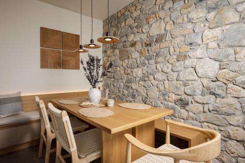 a dining room with a wooden table and a stone wall at Elirion Luxury Home II in Kamária