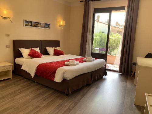 a bedroom with a large bed with red pillows at Logis Hôtel Restaurant Le Top du Roulier in Capendu