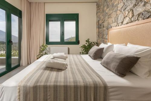 a bedroom with a large white bed with a stone wall at Elirion Luxury Home II in Kamária