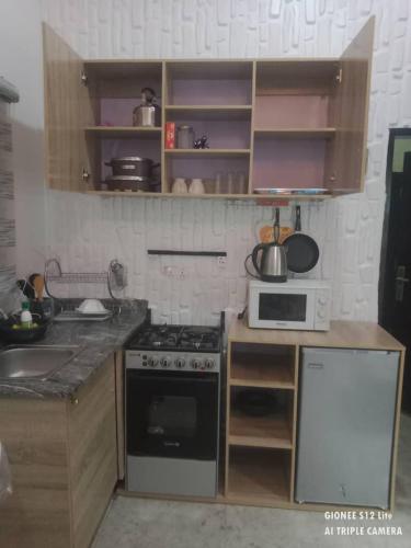 a small kitchen with a stove and a microwave at Cozybay Apartments in Wupa