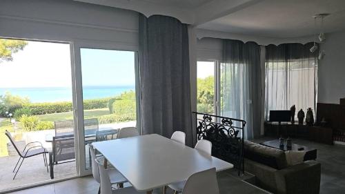a living room with a white table and a view of the ocean at Villa Mare Azul, 300sqm Seafront villa 6 bedrooms, 6 bathrooms in Polykhrono