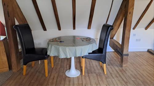 a table with two black chairs and a table with at Top Floor Malthouse Studio Apartment in Much Wenlock