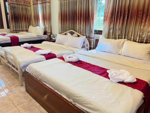 three beds in a room with towels on them at Lotus Blanc Homestay Villa in Battambang