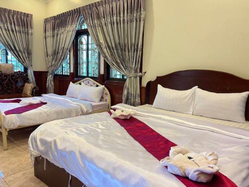 two beds with teddy bears sitting on them in a bedroom at Lotus Blanc Homestay Villa in Battambang
