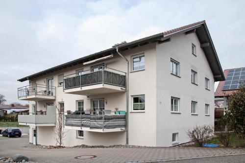 a white apartment building with balconies and a parking lot at Wohnung Sonnentau in Bad Wurzach
