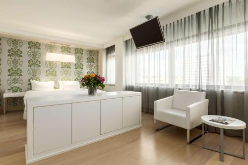een slaapkamer met een wit bed en een witte stoel bij NH Amsterdam Zuid in Amsterdam