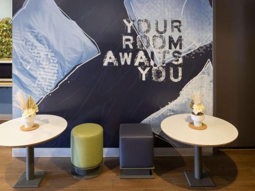 two tables and chairs with a sign that saysour roomamine you at Ibis Budget - Casula Liverpool in Liverpool