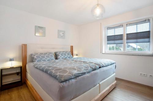 a white bedroom with a bed and a window at Wohnung Sonnentau in Bad Wurzach