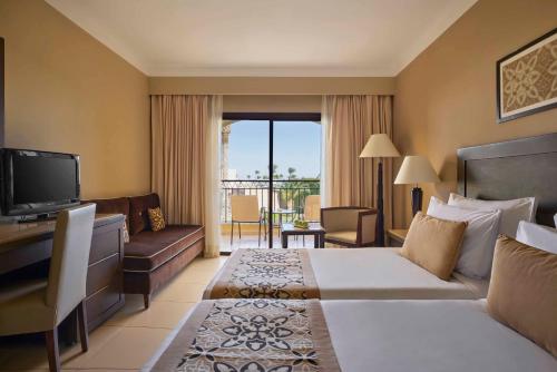a hotel room with a bed and a television at JAZ Neo Dar El Madina in Coraya Bay