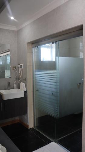 a bathroom with a glass shower and a sink at Charchoma Restaurant in Mombasa