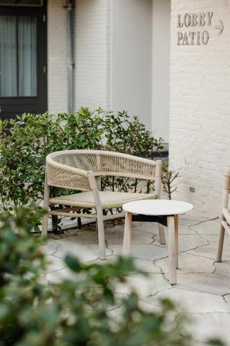 a bench and a stool in front of a building at Hotel Bommelje in Domburg