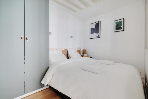 - une chambre blanche avec 2 lits et un miroir dans l'établissement Magnifique apartment in the Marais - PARIS, à Paris