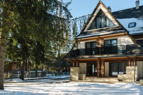 a house in the snow next to a tree at Zwierzyniecka Residence in Zakopane