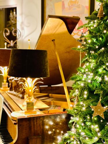 a christmas tree and a lamp on a piano at Hôtel VCB Ciney Centre-ville in Ciney