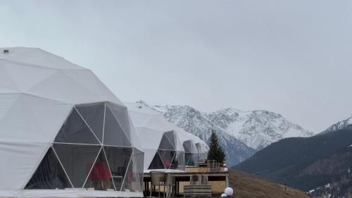 a group of domed buildings with mountains in the background at Asman Glamping in Karakol
