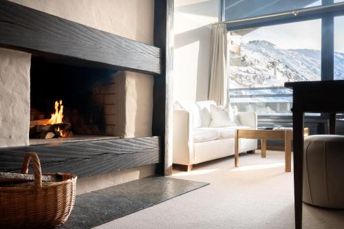 a living room with a fireplace with a couch and a chair at A-ROSA Hotel Thurnher's Alpenhof in Zürs am Arlberg