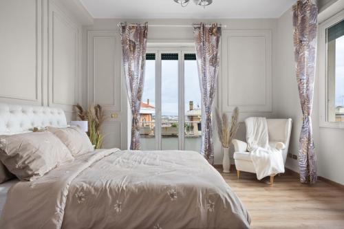 a white bedroom with a bed and a chair and windows at Maison G - new design apartment with balcony in Rome
