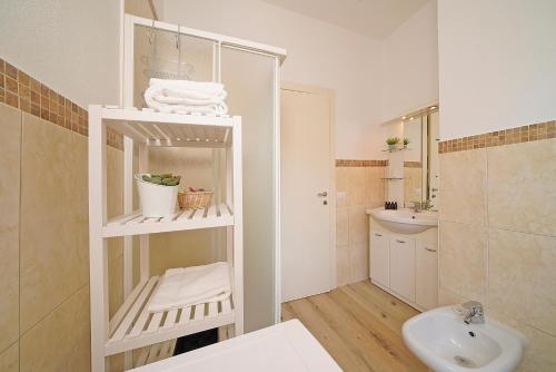 een badkamer met een wastafel en een witte plank met handdoeken bij PeschieraHome Apartments in Peschiera del Garda