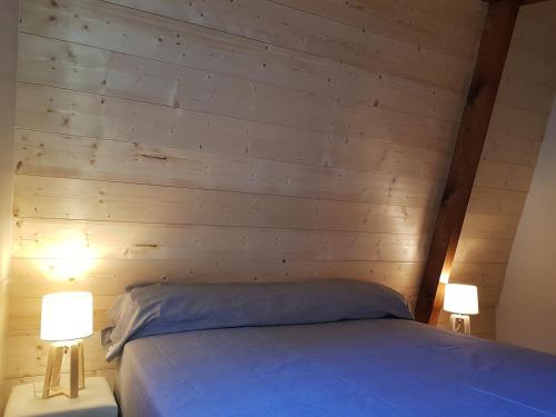- une chambre dotée d'un mur en bois avec un lit et deux lampes dans l'établissement Chalet sur les hauteurs des Angles, aux Angles