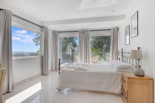 a white bedroom with a bed and a large window at Entrada Suite in Portimão