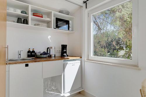 a kitchen with white cabinets and a window at Entrada Suite in Portimão