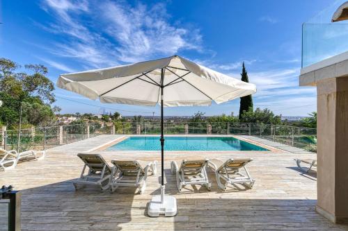 a white umbrella and chairs next to a swimming pool at Entrada Suite in Portimão
