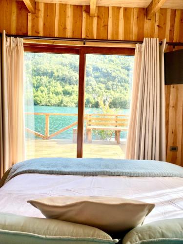 a bedroom with a bed and a large window at Refugio del Chucao in Llanada Grande