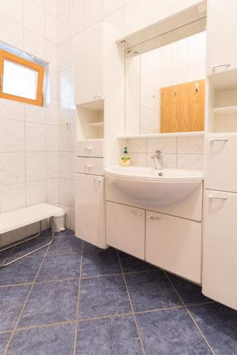 a white bathroom with a sink and a mirror at Apartments Sunset near the sandy beach - by TA Leut Agency in Privlaka