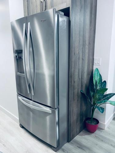 a stainless steel refrigerator in a kitchen with a plant at Modern 2 bedroom guest suite with AC in Calgary