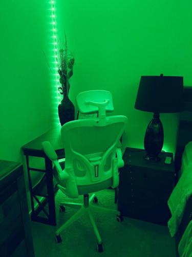 a green room with a chair and a lamp at Modern 2 bedroom guest suite with AC in Calgary