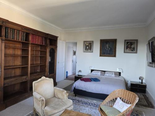 - une chambre avec un lit, une chaise et des étagères dans l'établissement Les Embruns - Le Port, à Deauville