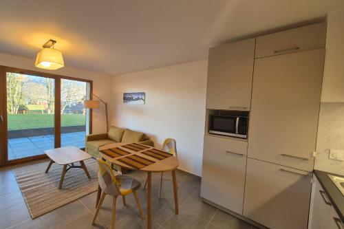 Il comprend une cuisine équipée d'une table, d'un canapé et d'un réfrigérateur. dans l'établissement NEW ! Altitude 1327 Residence at the foot of the slopes, à La Féclaz