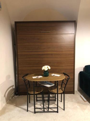 a table with chairs and a vase of flowers on it at Apartmány na Náměstí in Český Brod