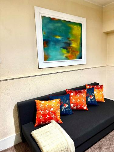 a black couch with colorful pillows under a painting at London Bridge 1-Bedroom Douglas building Entire Apartments in London