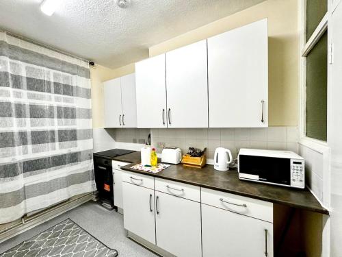 a small kitchen with white cabinets and a microwave at London Bridge 1-Bedroom Douglas building Entire Apartments in London