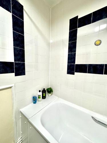 a white tub in a bathroom with black and white tiles at London Bridge 1-Bedroom Douglas building Entire Apartments in London