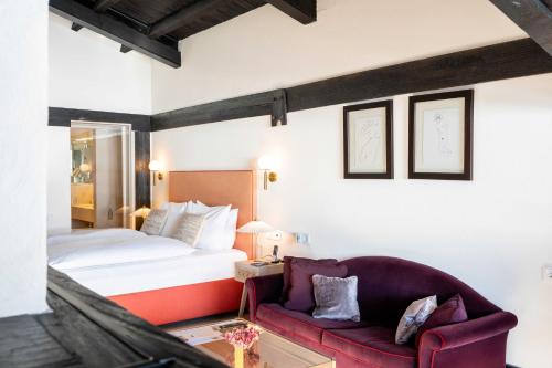 a hotel room with a bed and a red couch at A-ROSA Hotel Thurnher's Alpenhof in Zürs am Arlberg